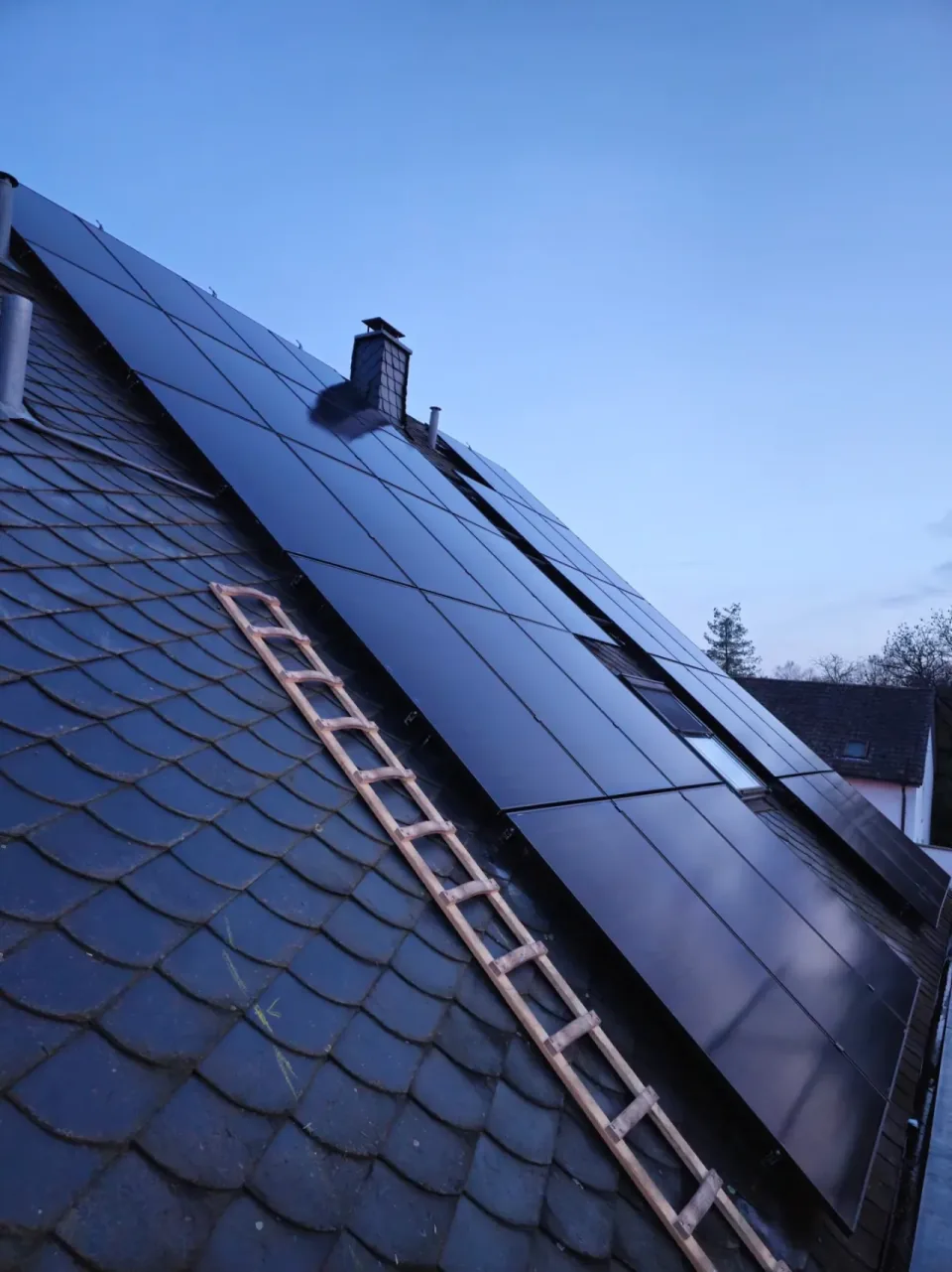 Solarmodule auf einem dunklen Dach mit Schornstein