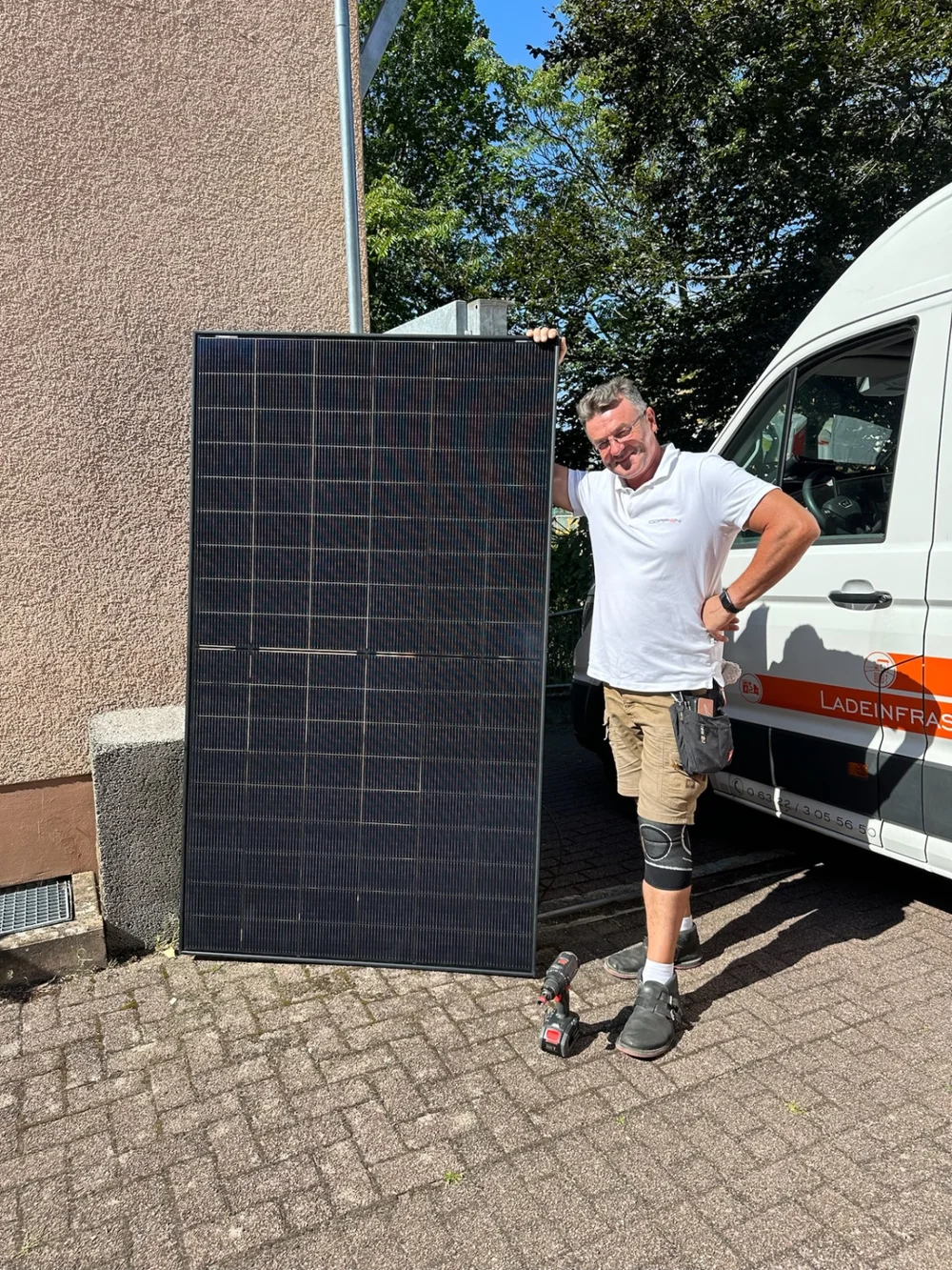 Person im COPPEN-Polo mit Solarmodul vor einem Montagefahrzeug