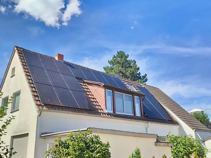 Giebelhaus mit vollschwarzen Solarmodulen unter blauem Himmel